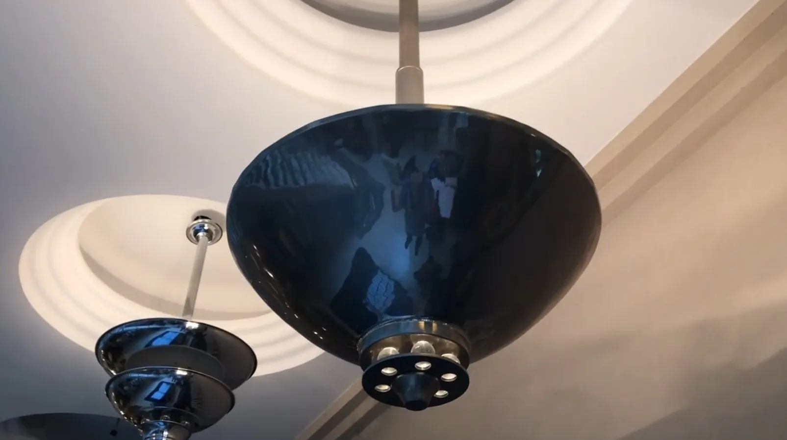 पुराना लटकता हुआ दीपक चमकदार फिनिश के साथ एक आधुनिक कमरे में है।