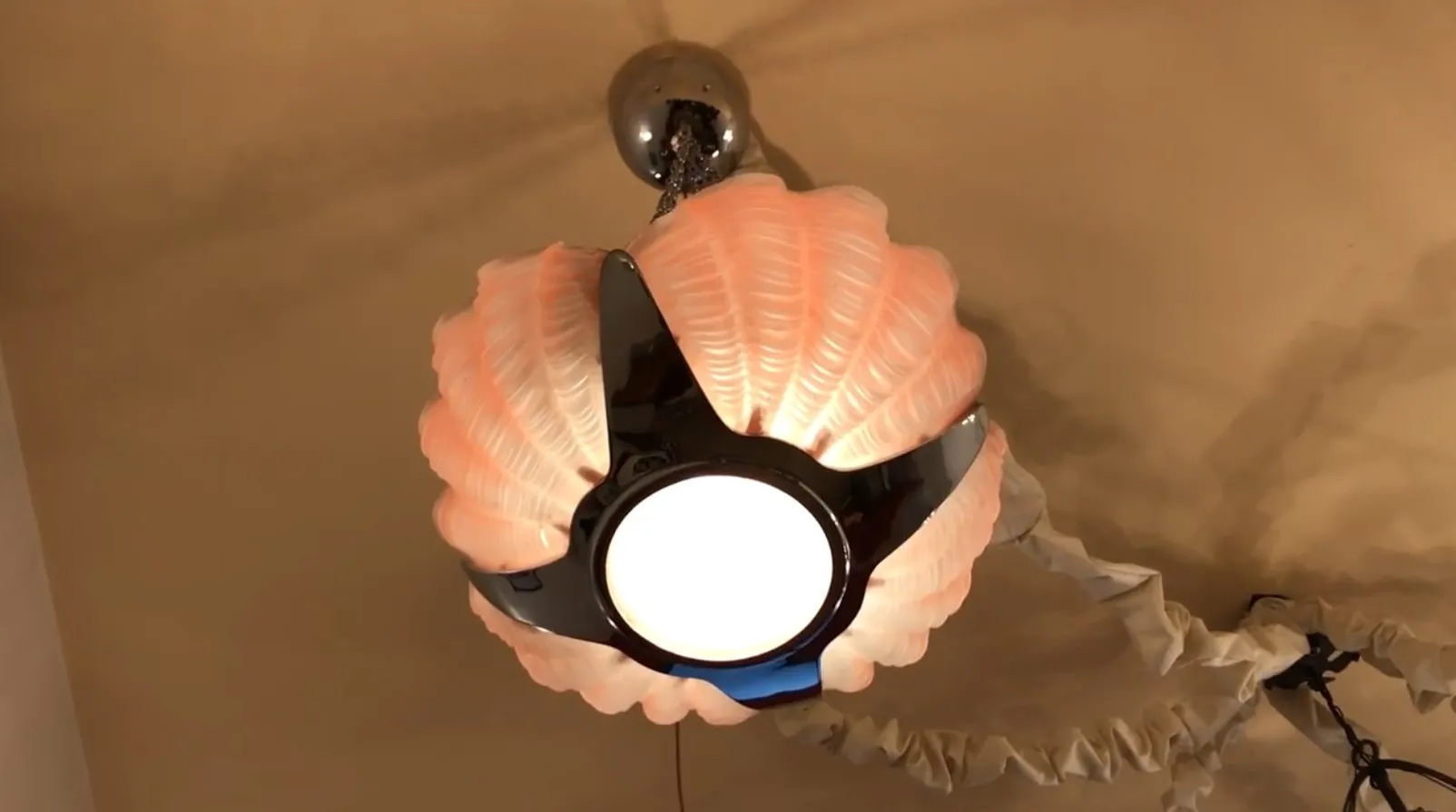 Lustre ancien avec design en forme de coquillage et lumière centrale brillante.