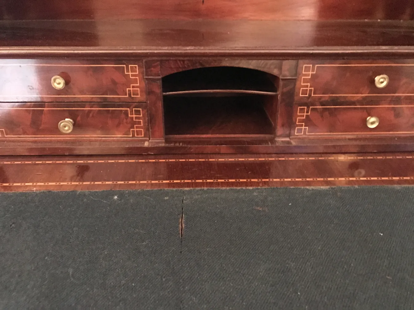 Bureau ancien en bois foncé avec deux tiroirs visibles et un espace ouvert au milieu.