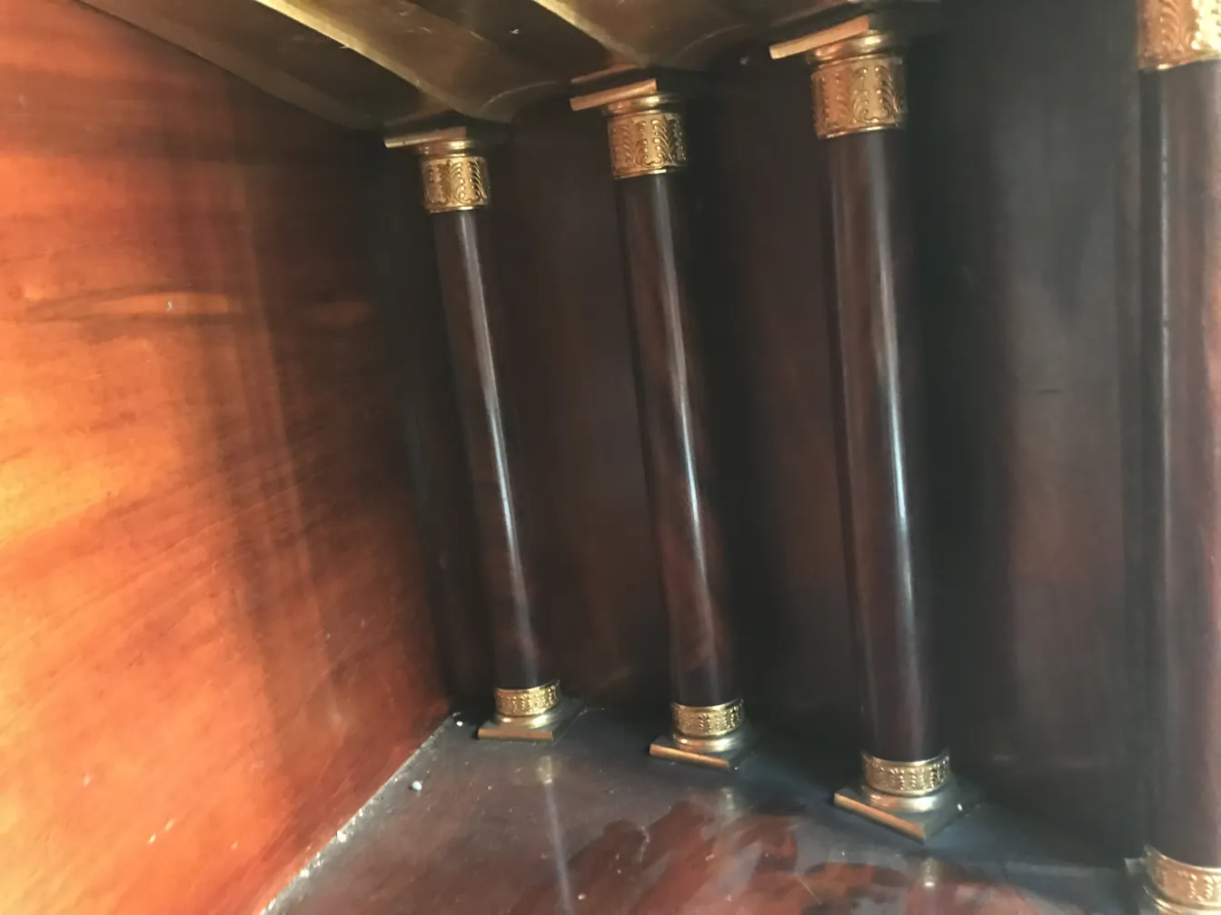 Vista de un antiguo escritorio con patas de bronce y madera oscura.