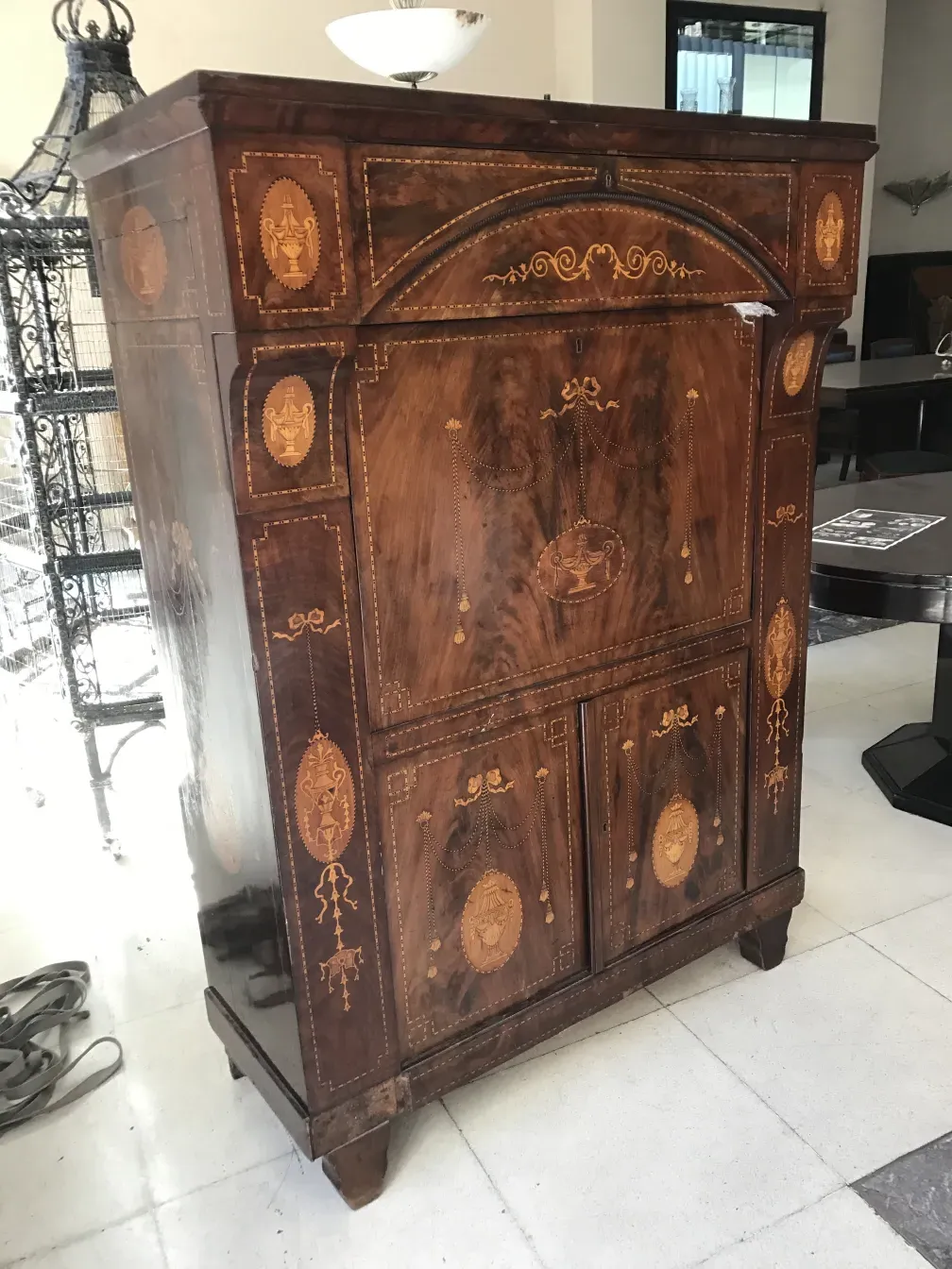 Scrivania antica in legno con decorazioni sul davanti, in un ambiente moderno.