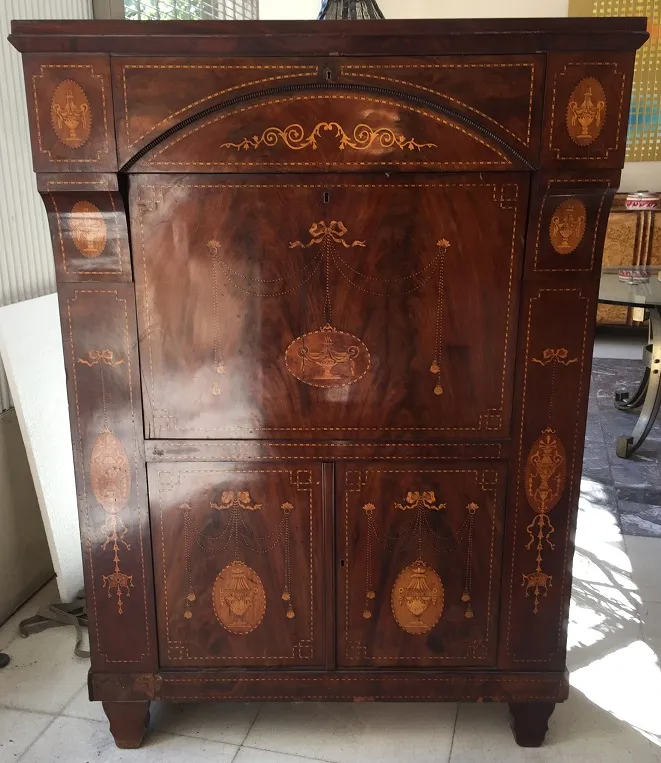 Escritorio antiguo de madera con detalles decorativos en bronce, ideal para un estudio elegante