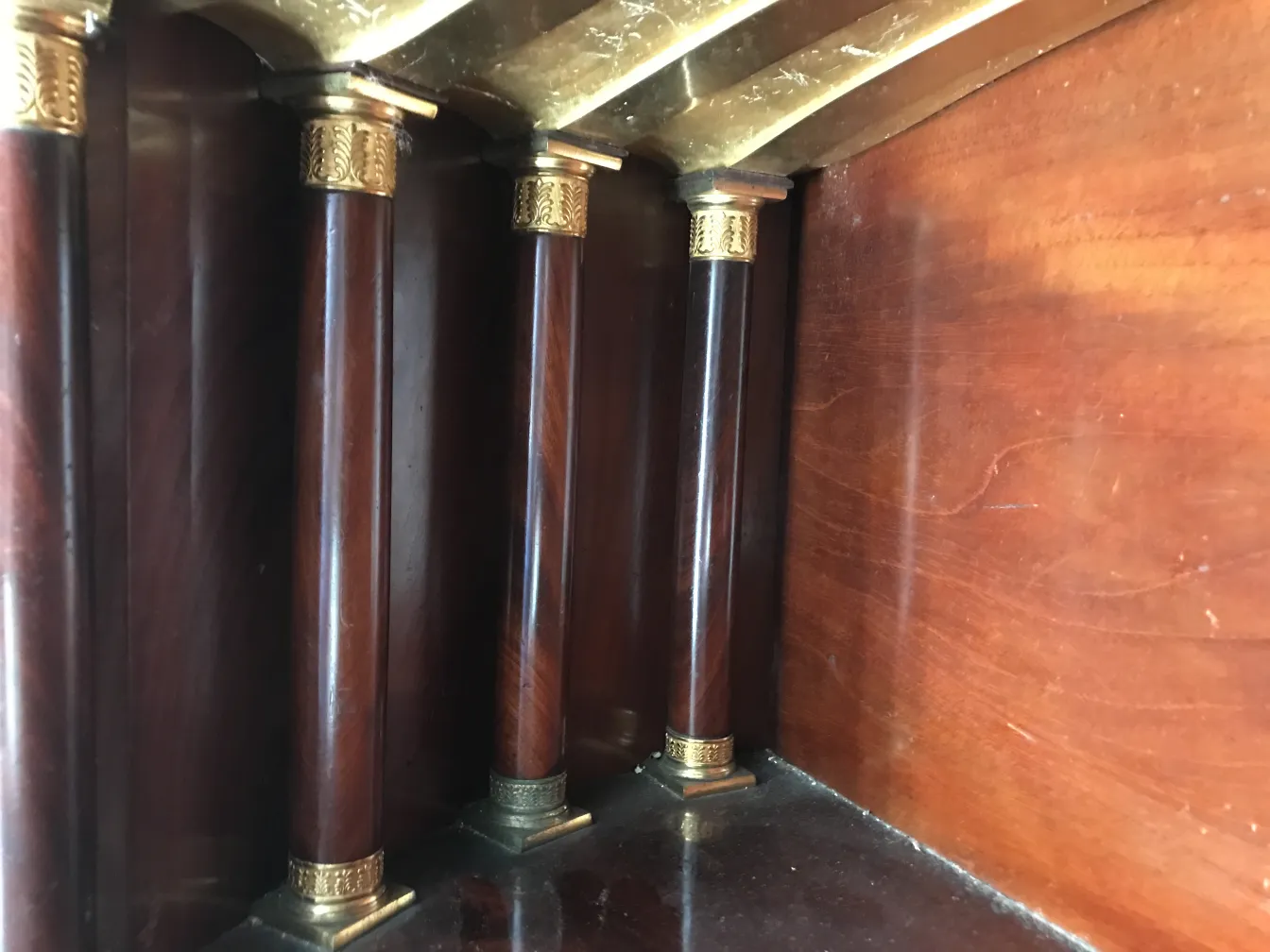 Escritorio antigo com pilares de madeira e detalhes dourados no topo.