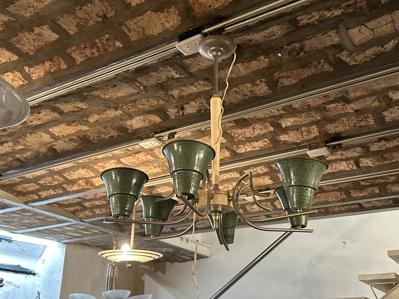 Lustre ancien avec abat-jours verts dans un cadre rustique.