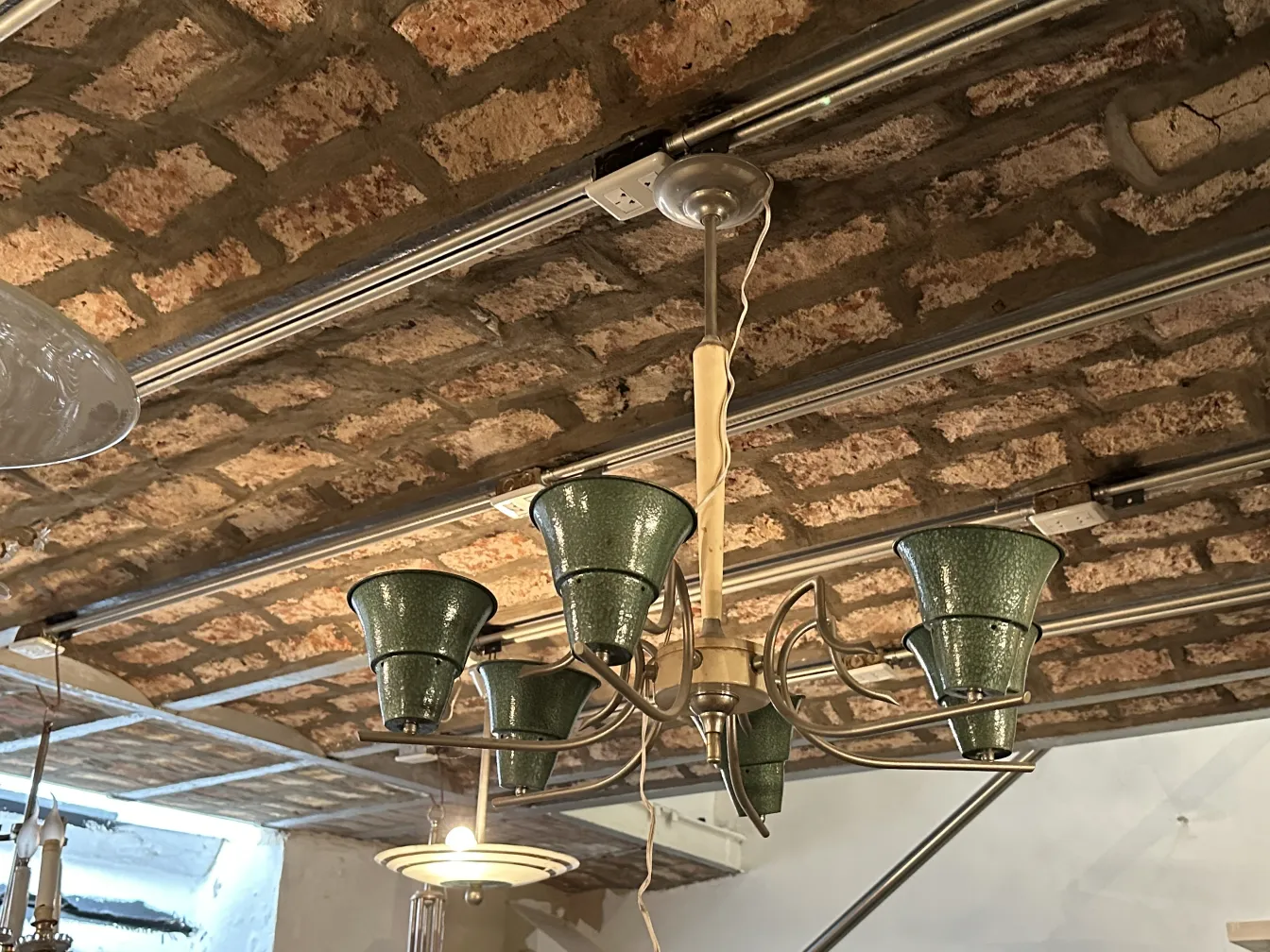 Lampada a sospensione antica con paralumi verdi in un ambiente rustico.