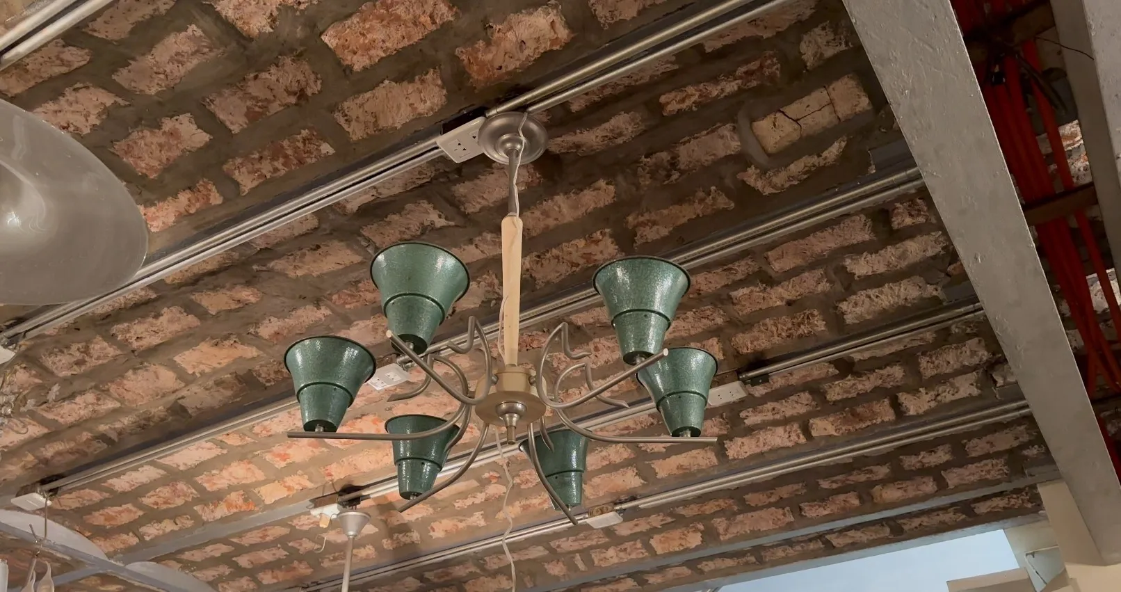 Antique hanging lamp with six green shades, rustic setting.