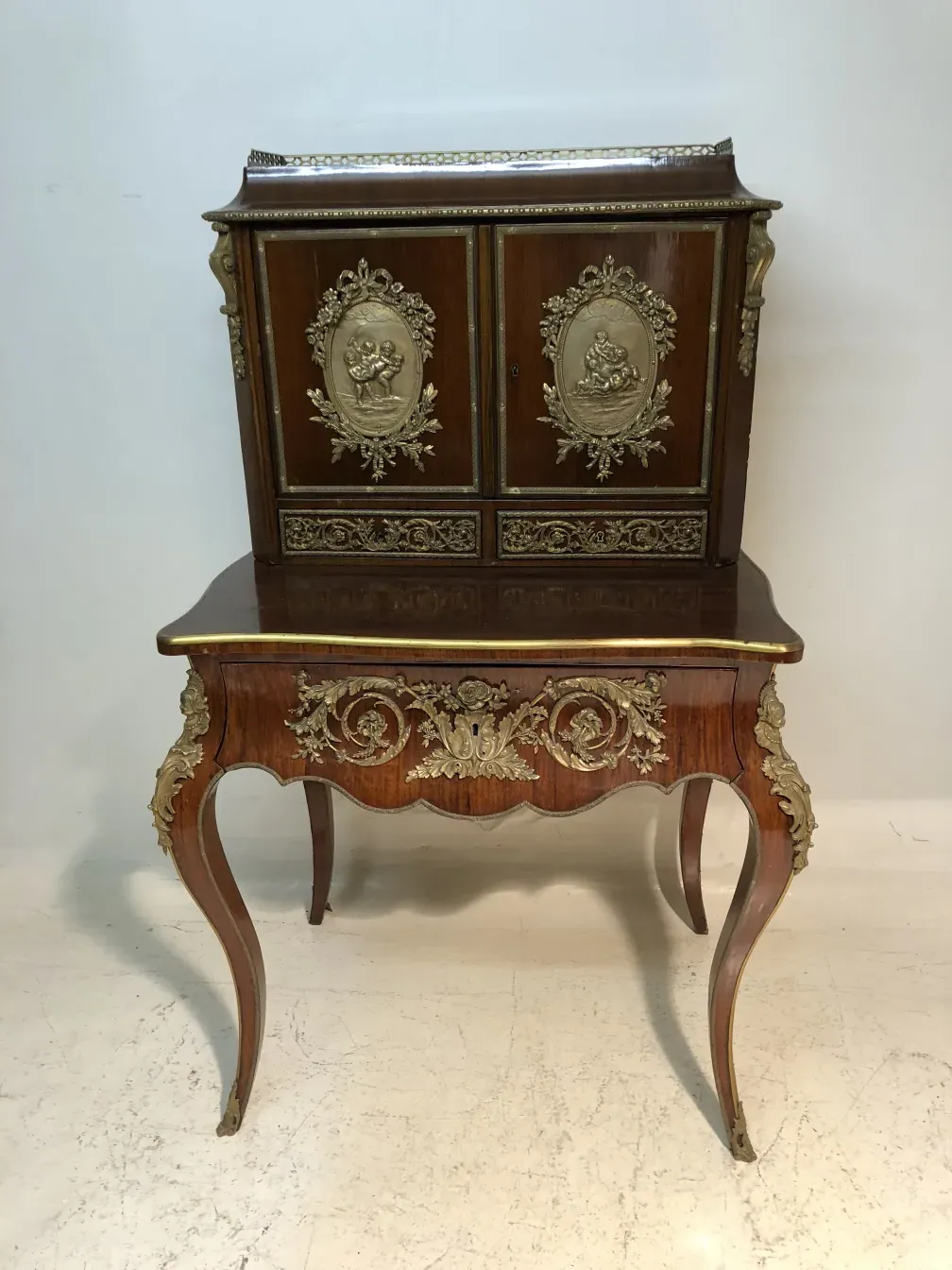 Bureau ancien avec deux tiroirs décorés en or.