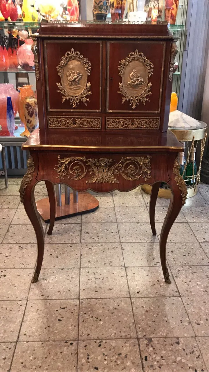 antique wooden desk with golden decorations and two drawers, surrounded by colorful decor