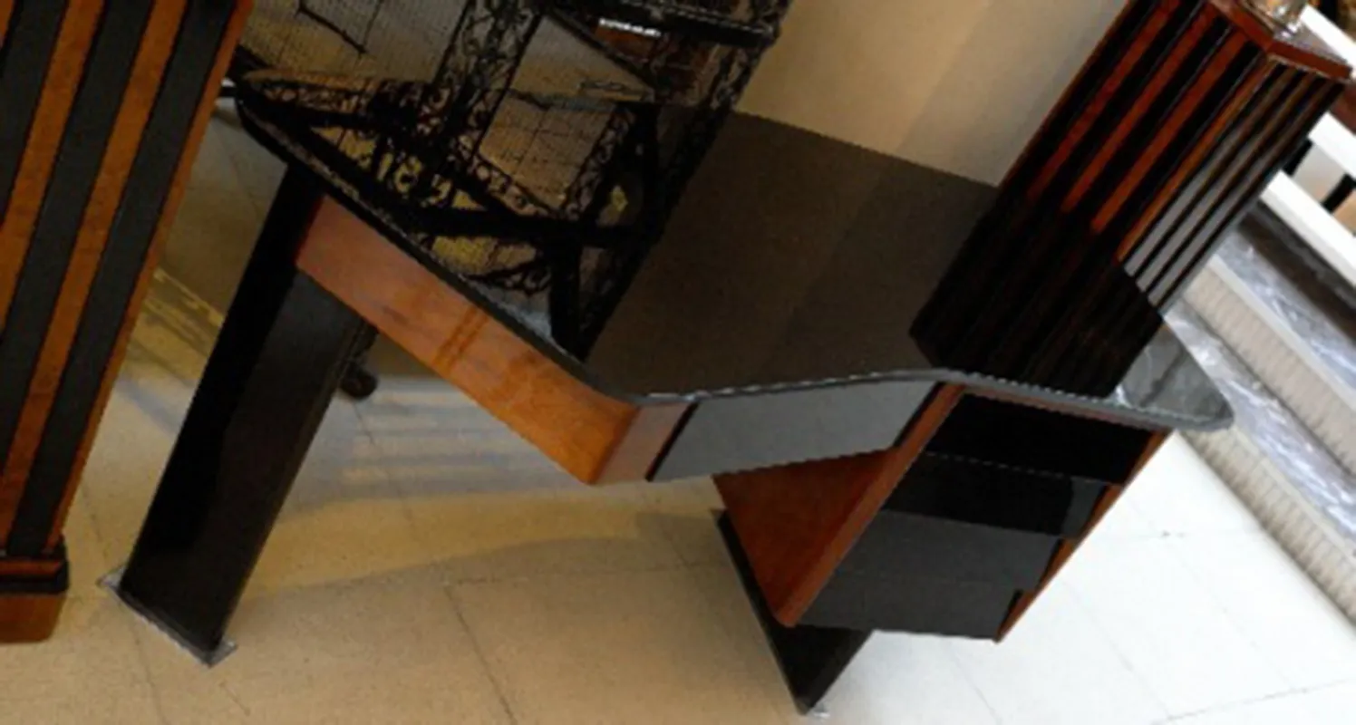 Scrivania antica con superficie nera e linee moderne, inserita in un ambiente elegante.