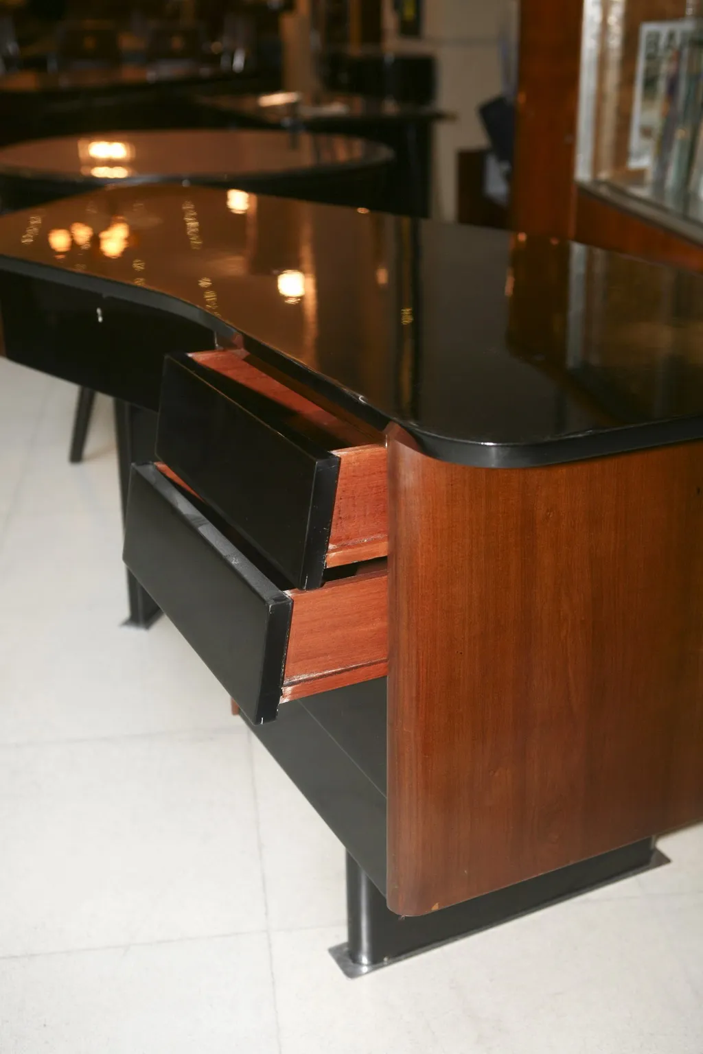 Vista laterale di una scrivania antica con finitura nera e legno, con due cassetti