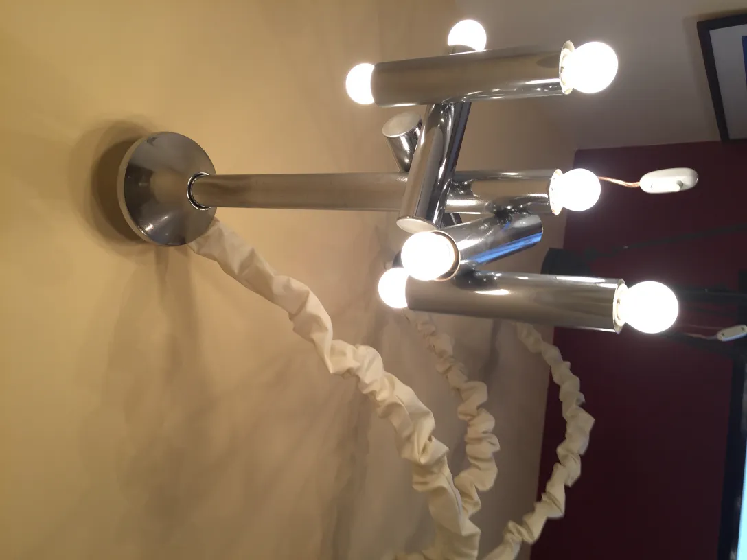 Lampada a sospensione antica con diverse lampadine luminose, in un ambiente illuminato.