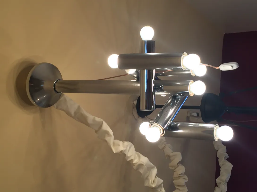 Antique hanging lamp with multiple bulbs against a light wall.