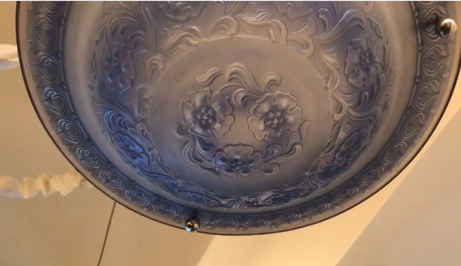 Lampada a sospensione antica con design floreale in rilievo.