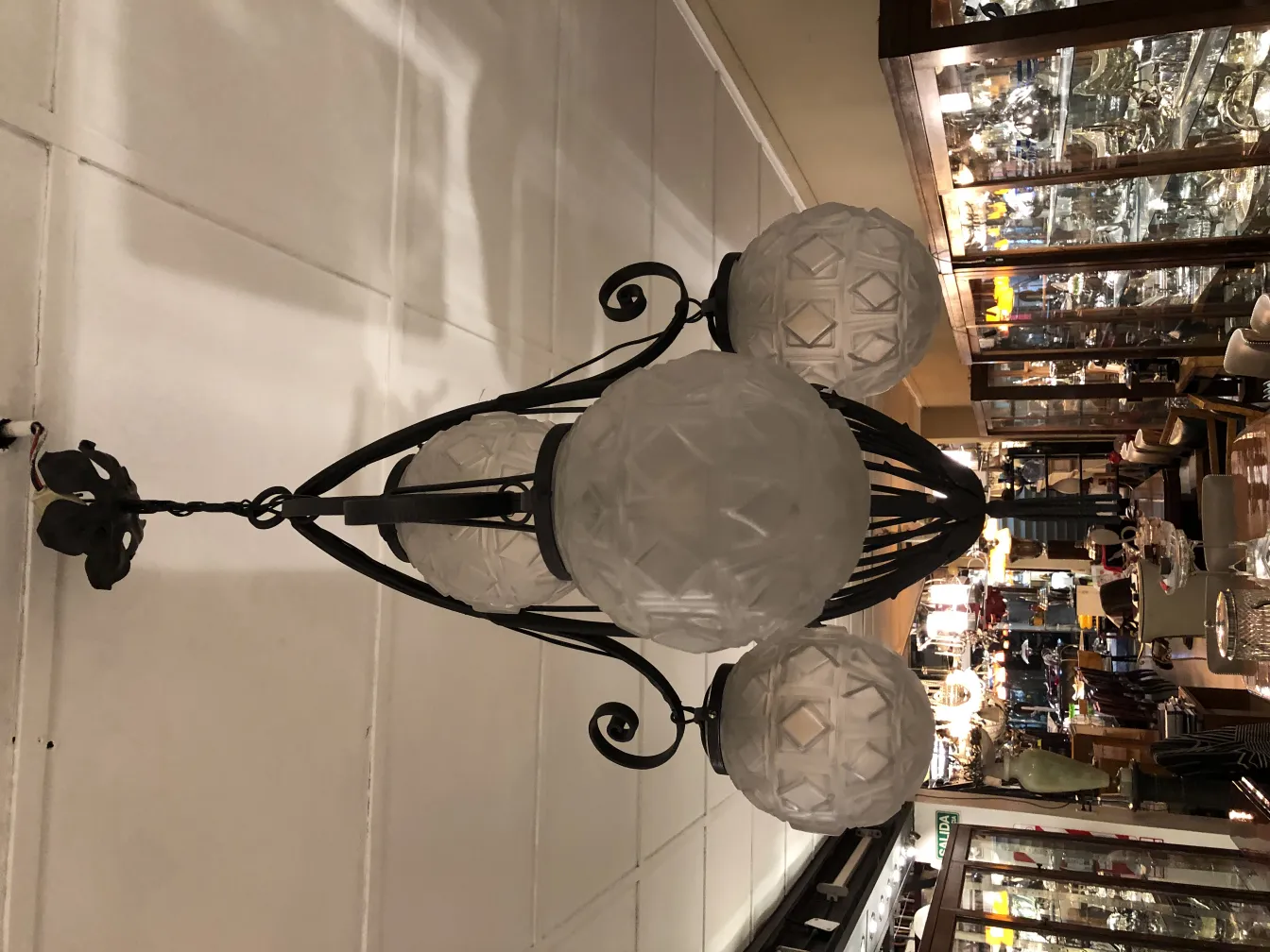 Lampada a sospensione antica con dettagli in vetro e sfondo di antiquariato.