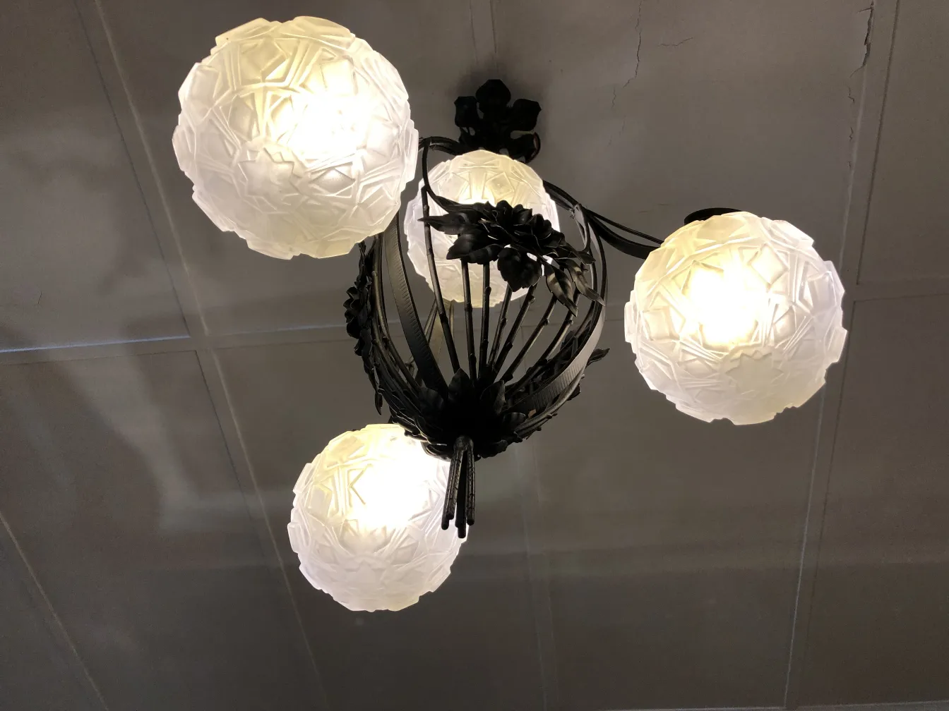 Lustre ancien avec des sphères blanches dans un cadre chaleureux