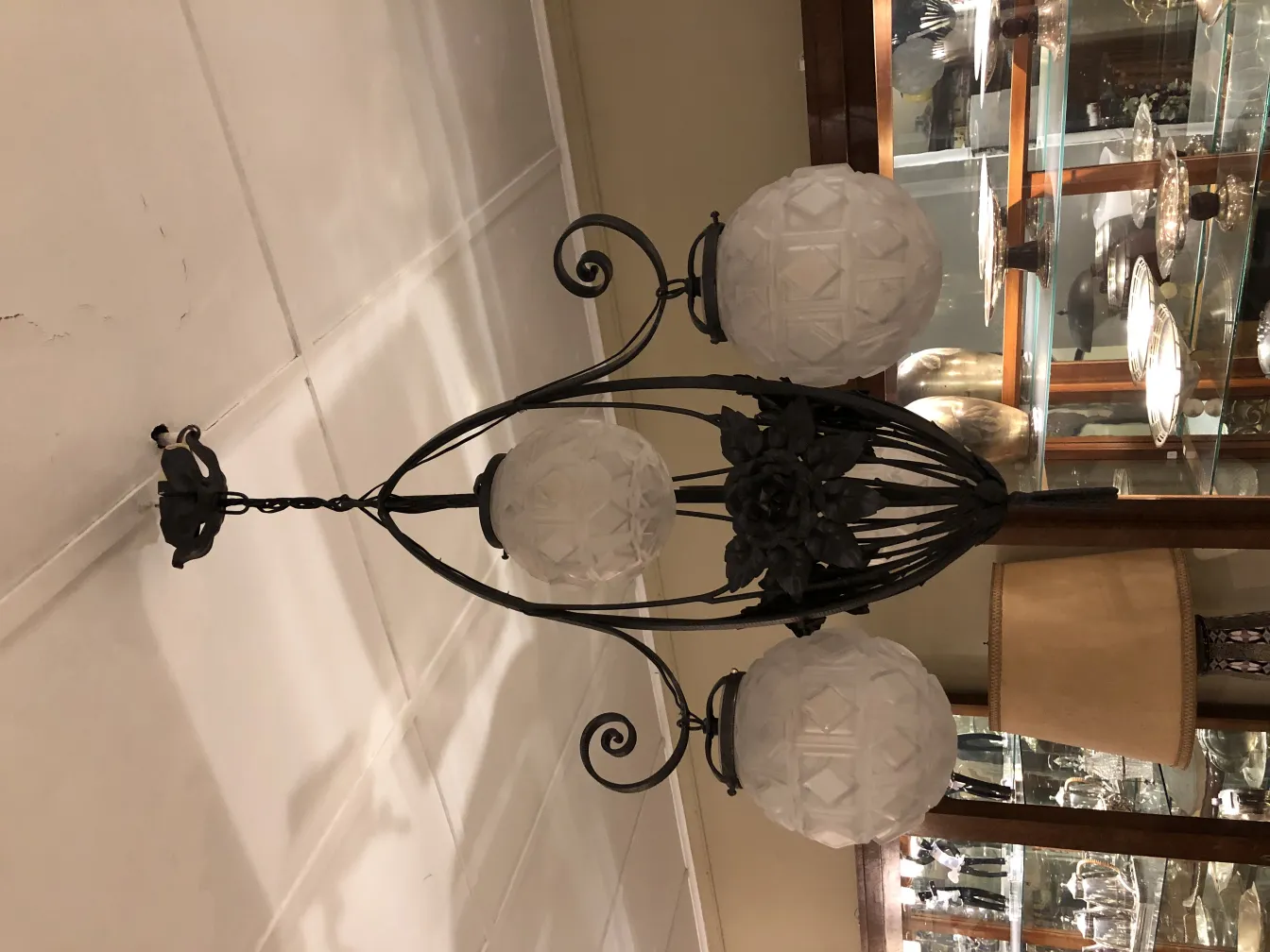 Lámpara de techo antigua con esferas de vidrio blanco en un ambiente acogedor.