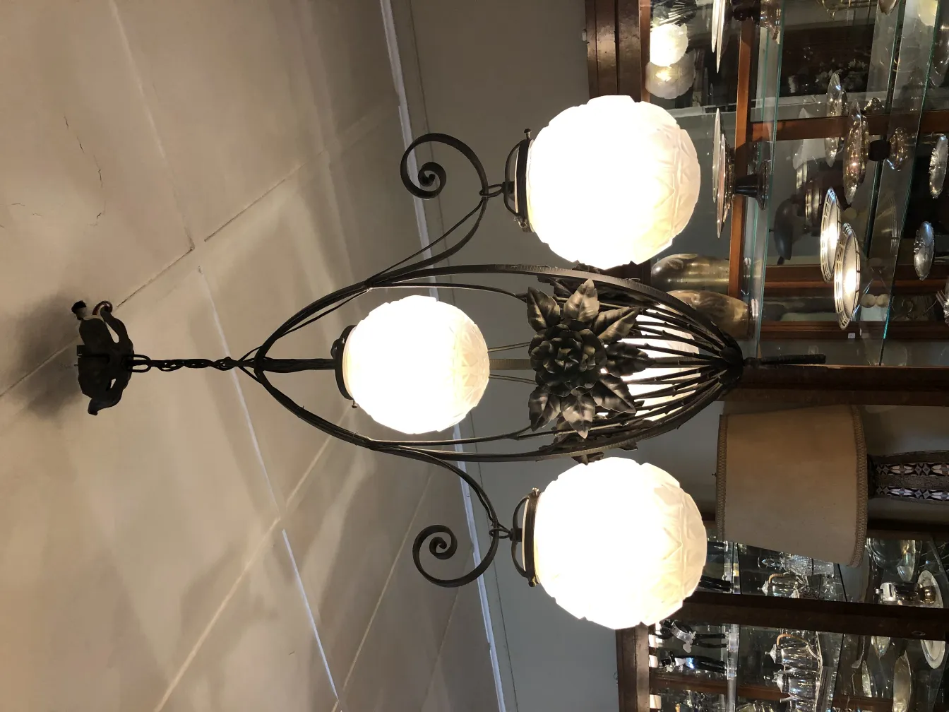 Antique hanging lamp with three glass globes in an elegant setting.