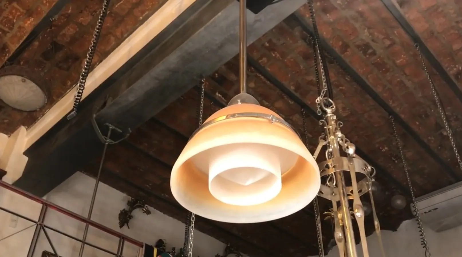 Lâmpada de teto antiga em um ambiente rústico, projetada por Peter Behrens, com luz suave e formas elegantes.