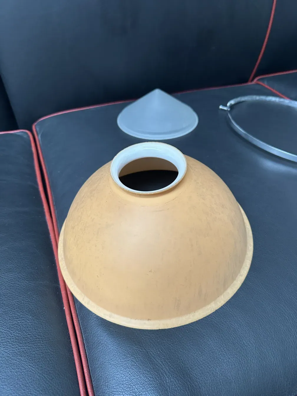 Lâmpada de teto antiga de Peter Behrens em um ambiente escuro, com superfície suave e curva.