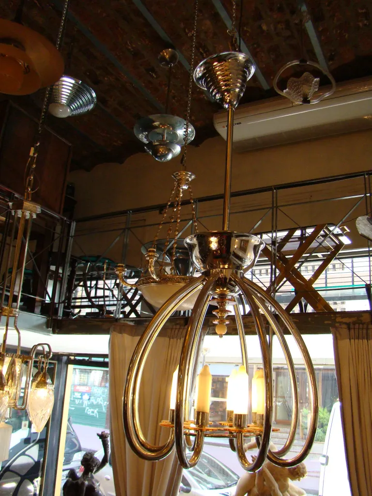 Lampada a sospensione antica con braccia eleganti e luce soffusa.