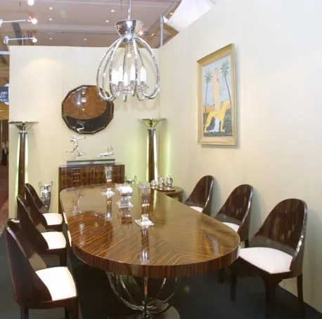 Lustre ancien avec plusieurs bras et un design élégant, dans un cadre moderne avec table et chaises.