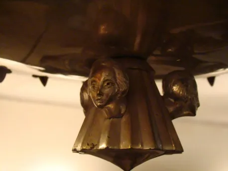 Lâmpada de teto antiga com figuras de cabeças decorativas.