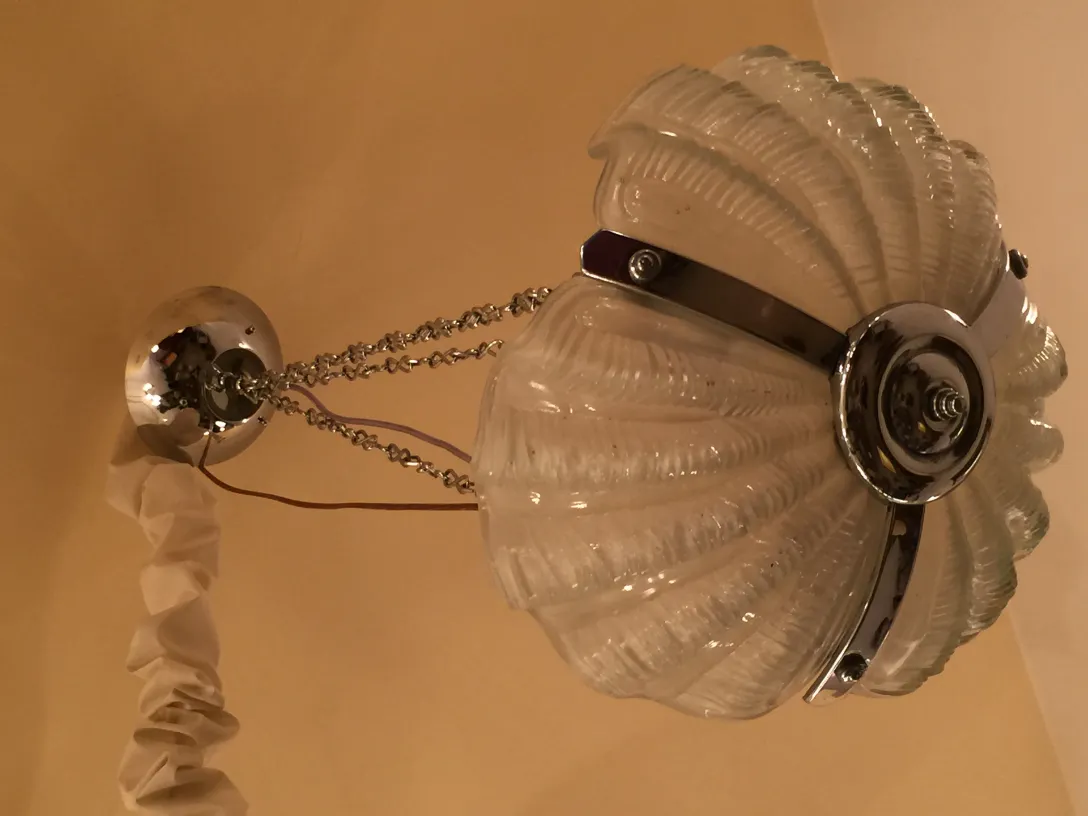 Lâmpada de teto antiga com vidro em forma de concha e detalhes cromados em um ambiente aconchegante.