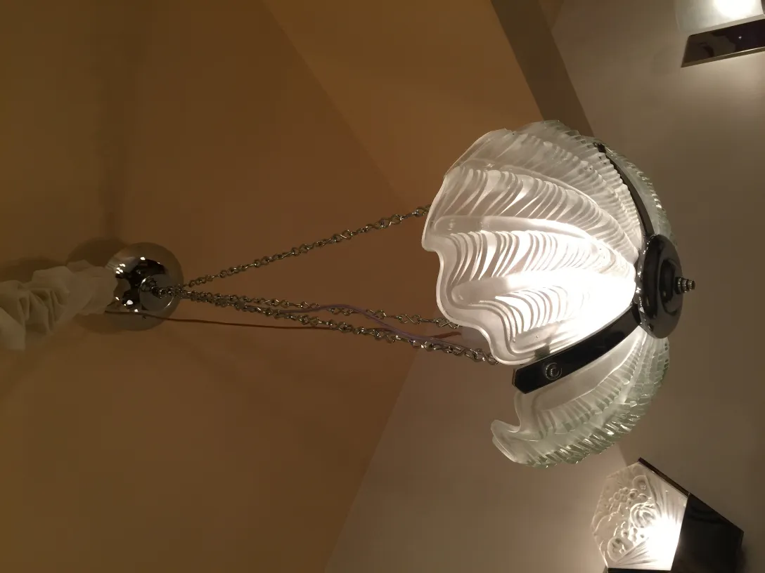 Lampada a sospensione antica con struttura lucida e design distintivo in un ambiente accogliente.