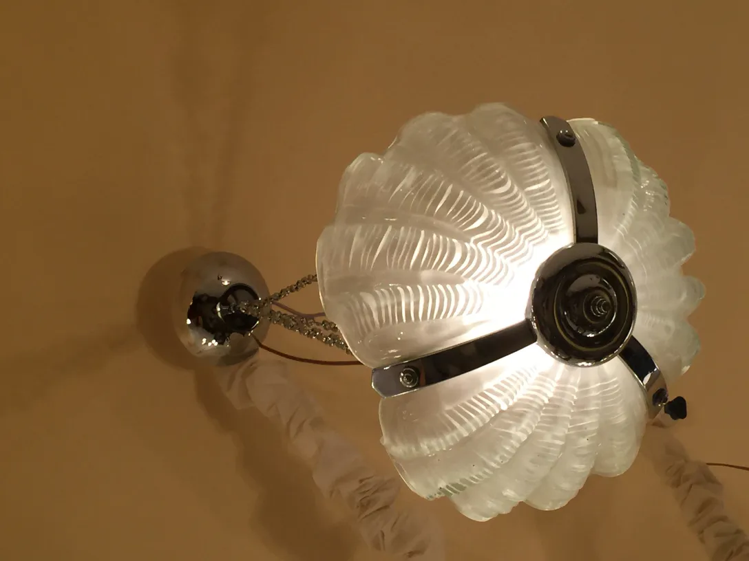 Lámpara de techo antigua de cristal con detalles plateados, iluminando un ambiente cálido.