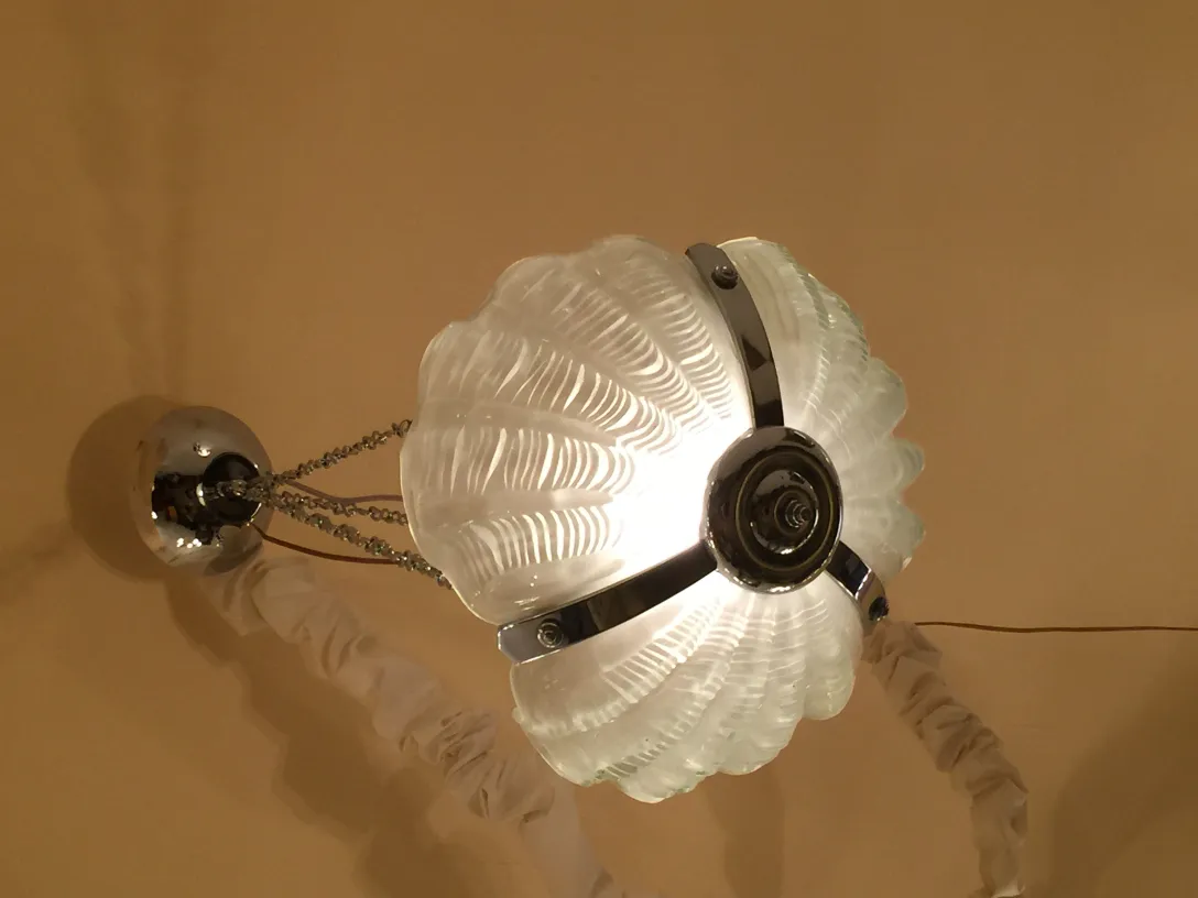 Lustre antique avec un design en coquillage et lumière chaude.