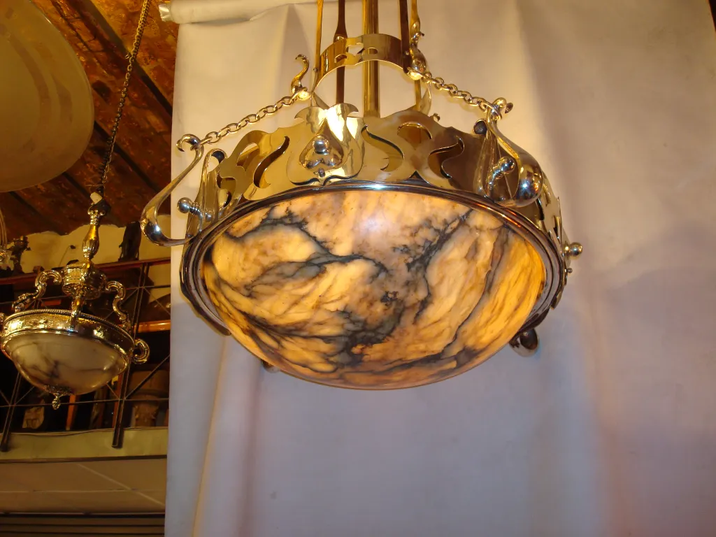 Antique hanging lamp with a golden base and decorative details, set in an elegant environment.