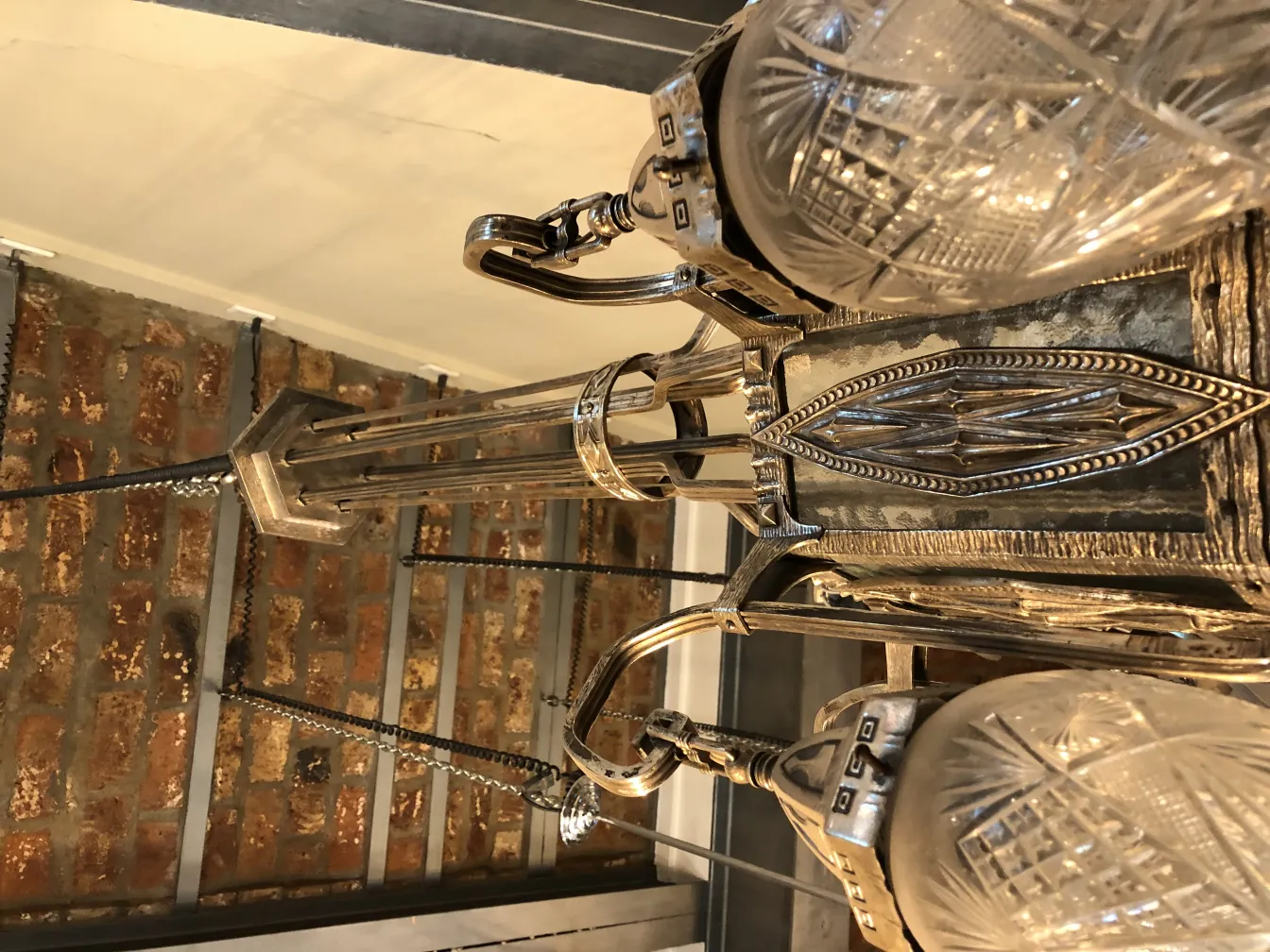 Antiga lampada de teto com cristais elegantes, pendurada em um ambiente aconchegante com paredes de tijolos.