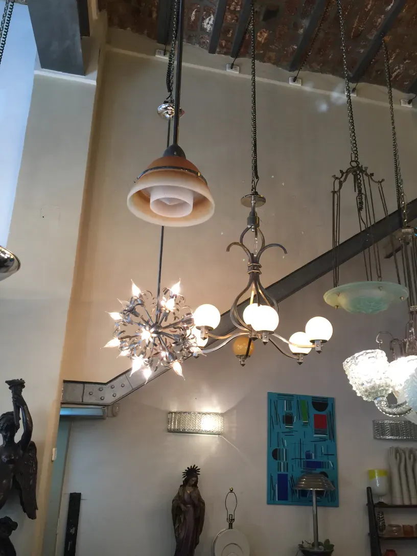 lampada a sospensione antica in stile ST Louis con design elegante e luce soffusa, circondata da altre lampade in un'atmosfera accogliente.