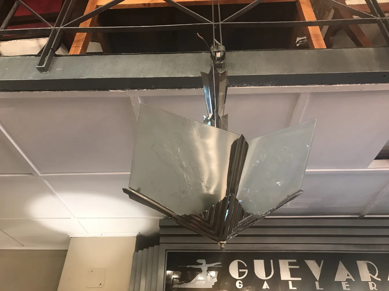 Lâmpada de teto antiga com design em vidro brilhante, suspensa em um ambiente elegante com móveis de madeira.