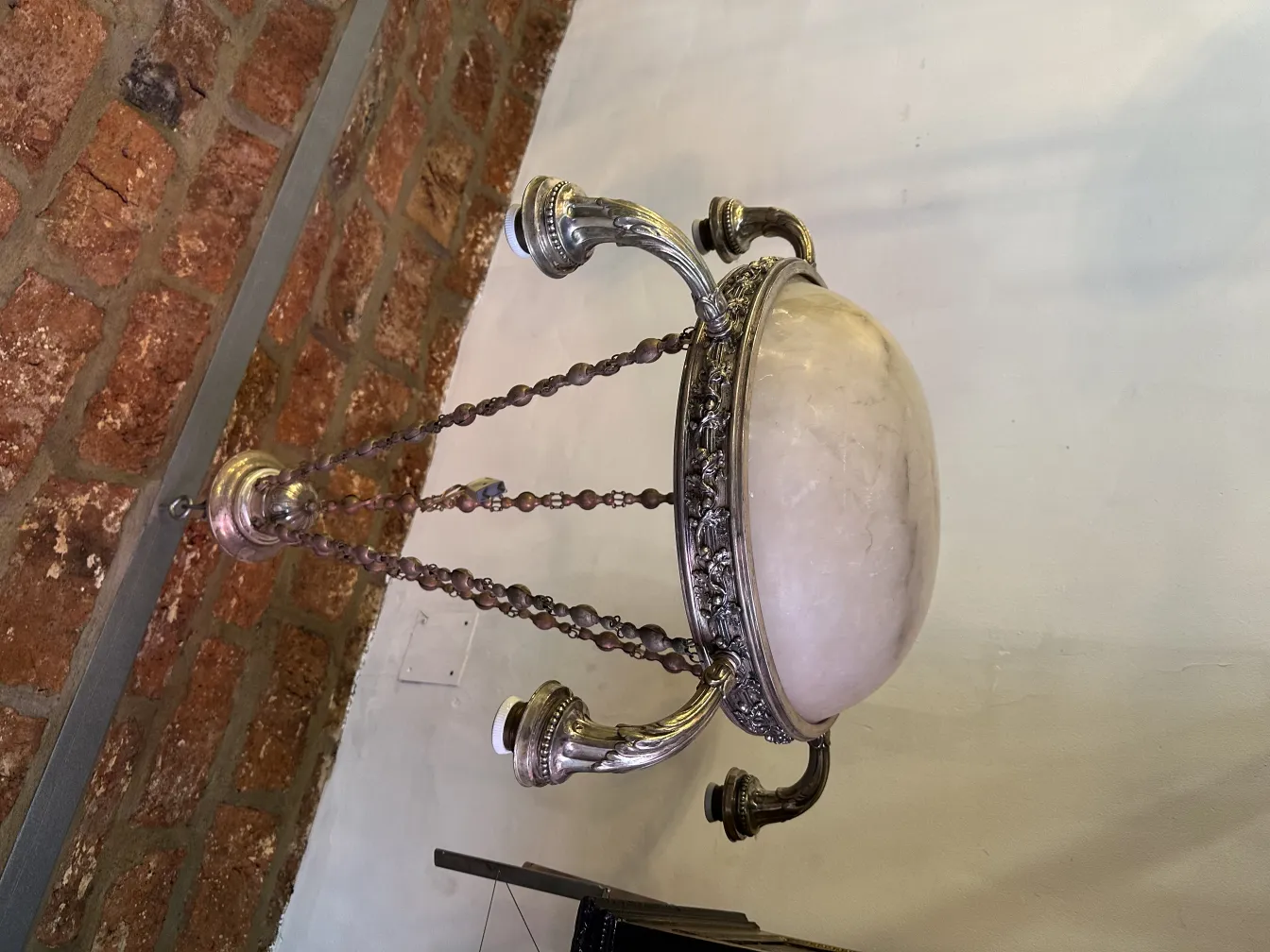 Lustre ancien au design élégant, orné de chaînes, dans un cadre rustique.