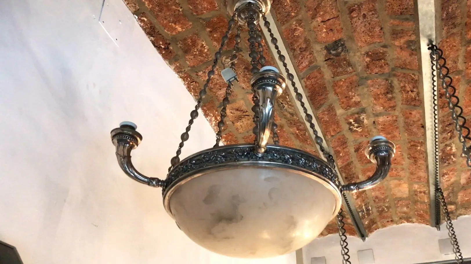 Lampada de teto antiga com correntes decorativas, luz suave.