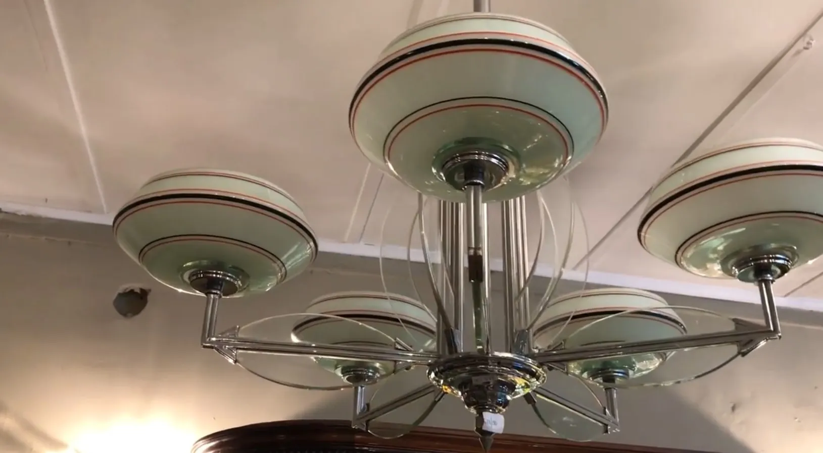 Lampada a sospensione antica con sei paralumi in vetro verde e dettagli decorativi.