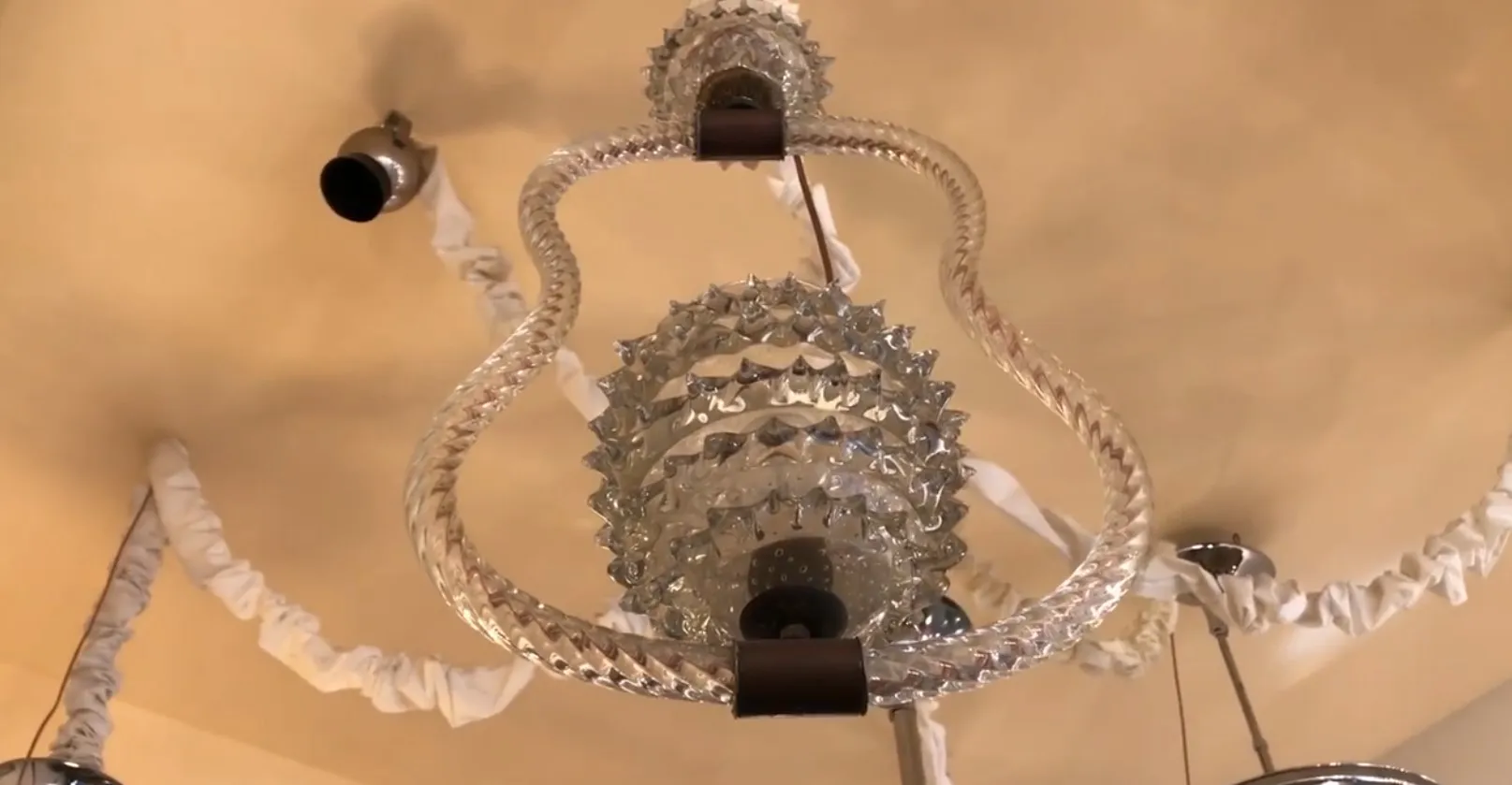 Antique hanging lamp with elegant spiral glass detail, Mazzega Murano, in a bright decorative environment.