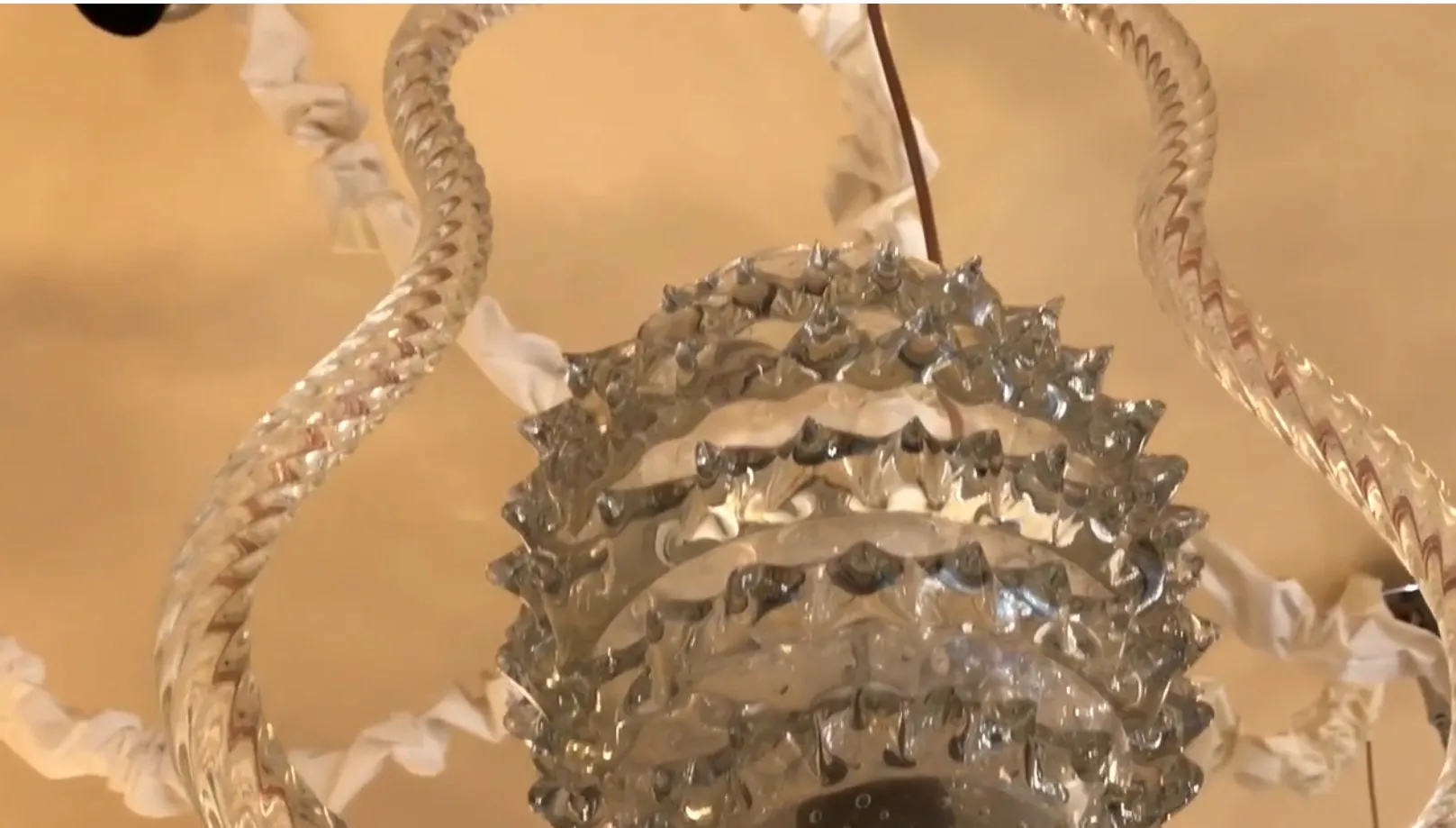 Antiga lâmpada de teto desenhada por Mazzega Murano com detalhes em cristal brilhante, pendurada de um teto limpo.