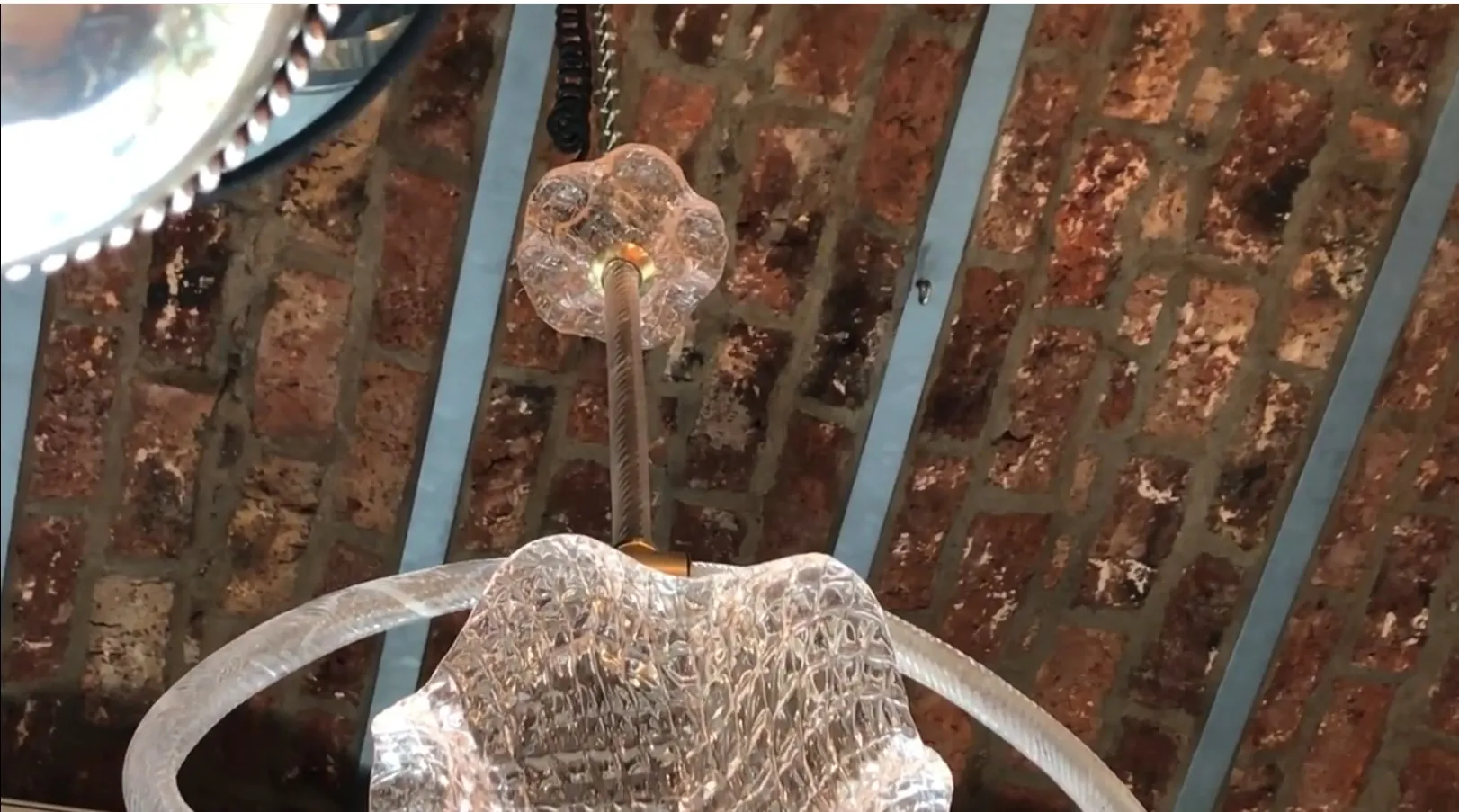 Ancien lustre avec des détails ronds et un design élégant. Atmosphère chaleureuse avec des briques apparentes.