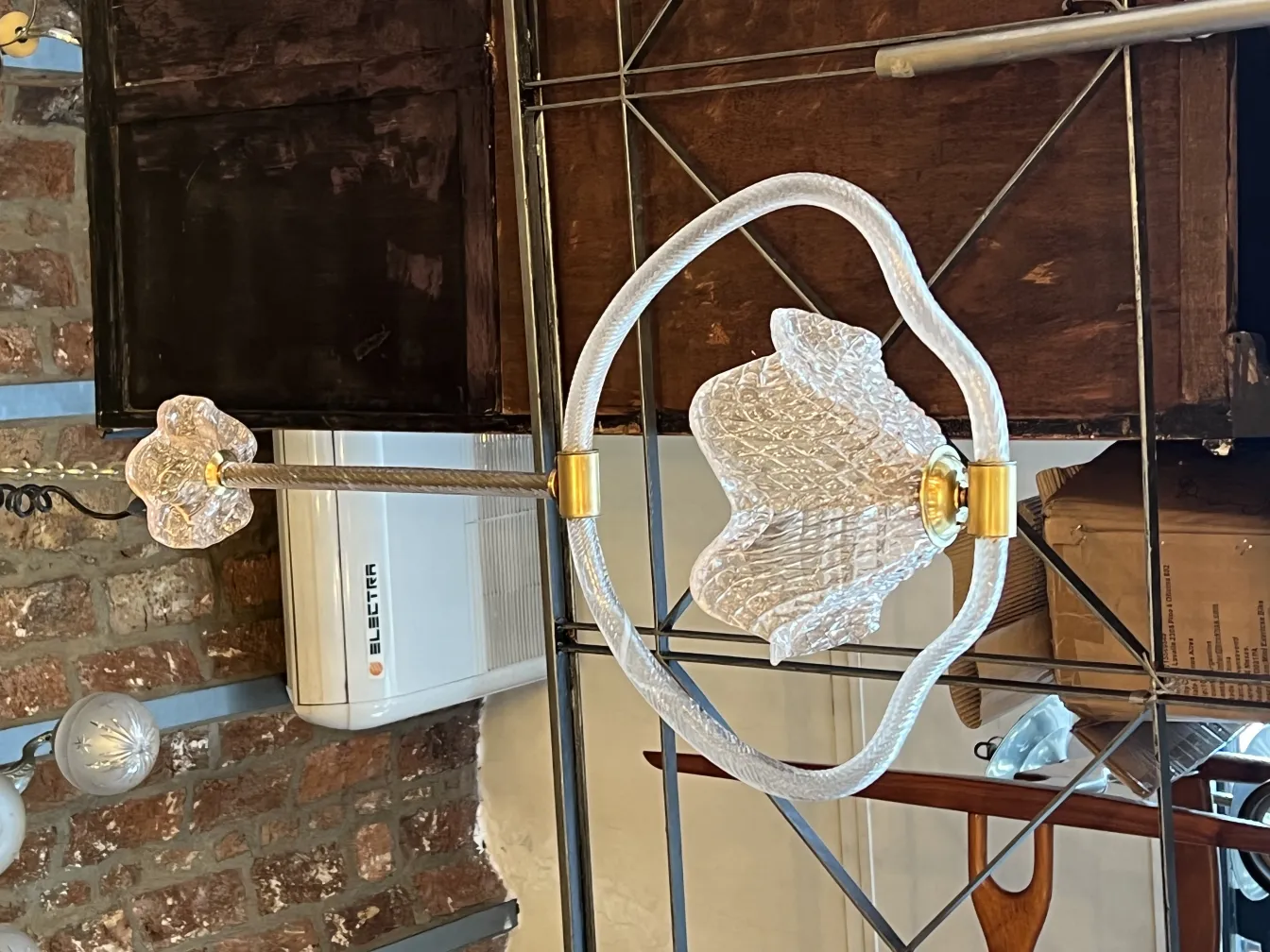 Lâmpada de teto antiga com design hexagonal e detalhes dourados contra um fundo de tijolos.