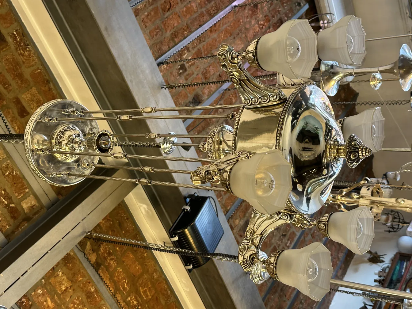 Lampada a sospensione antica con più luci e abat-jour bianchi, atmosfera accogliente.