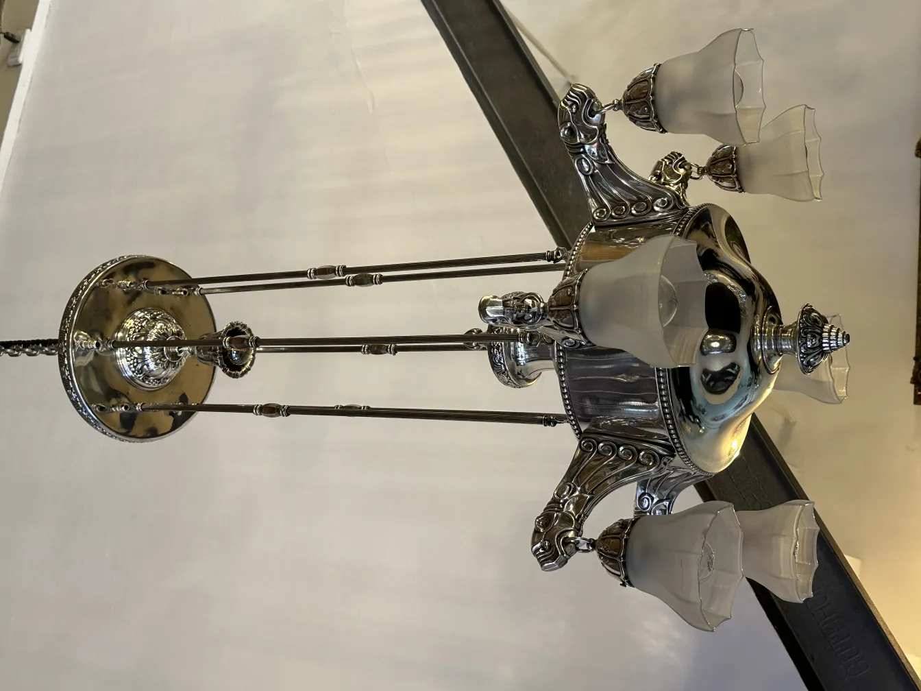 Ancien lustre avec trois abat-jours dans une ambiance chaleureuse.