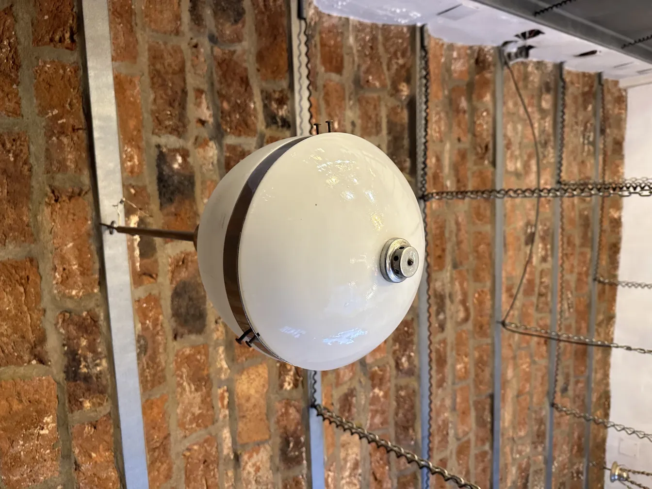 Antique white hanging lamp suspended in a room with brick walls.