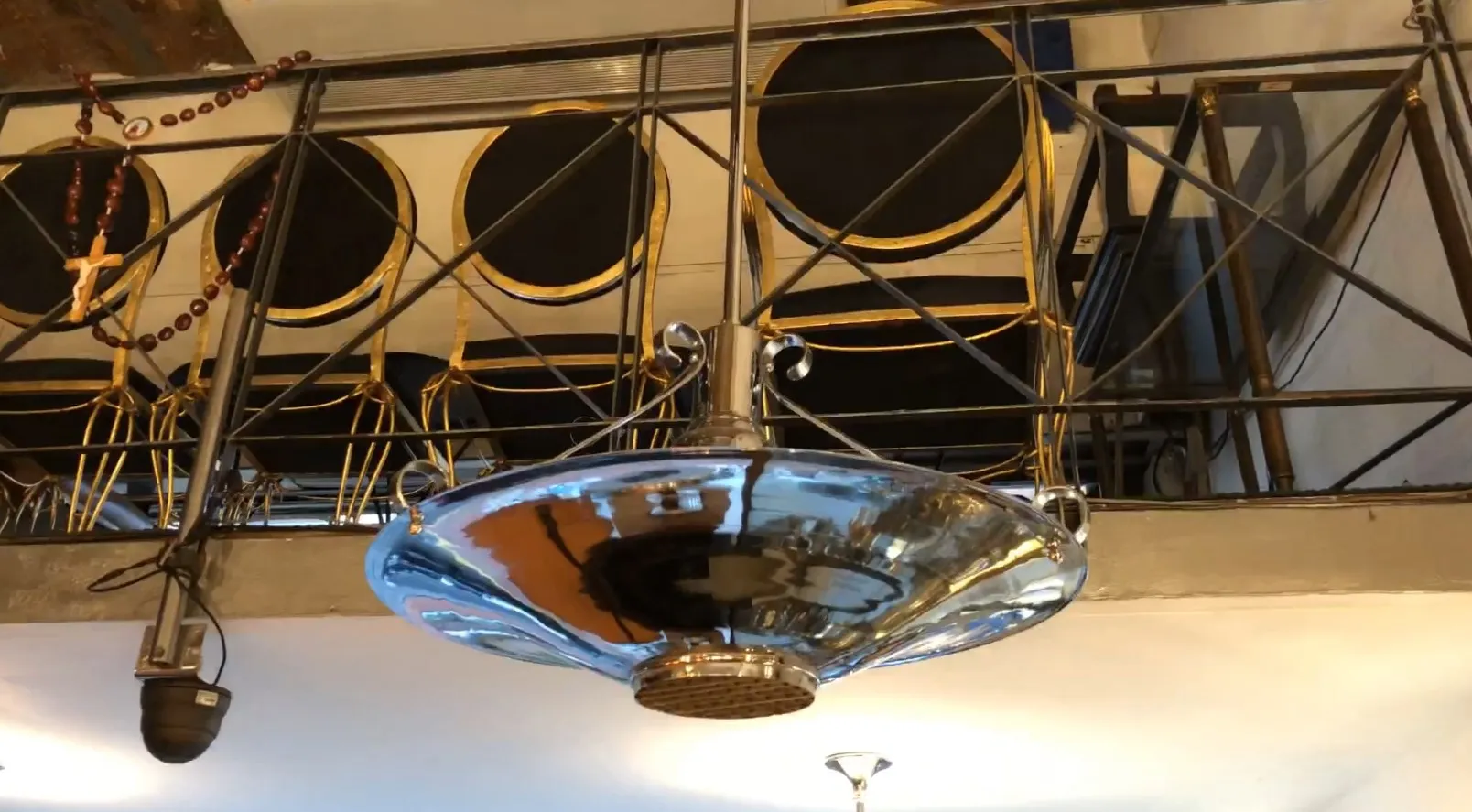 Lámpara de techo antigua con brillo, parte de una decoración. Sillas doradas al fondo.