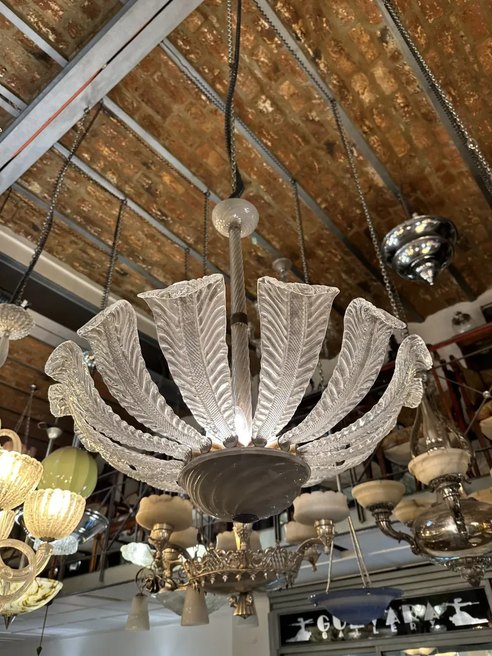 Lámpara de techo antigua con detalles decorativos en forma de hoja, iluminando ambiente.