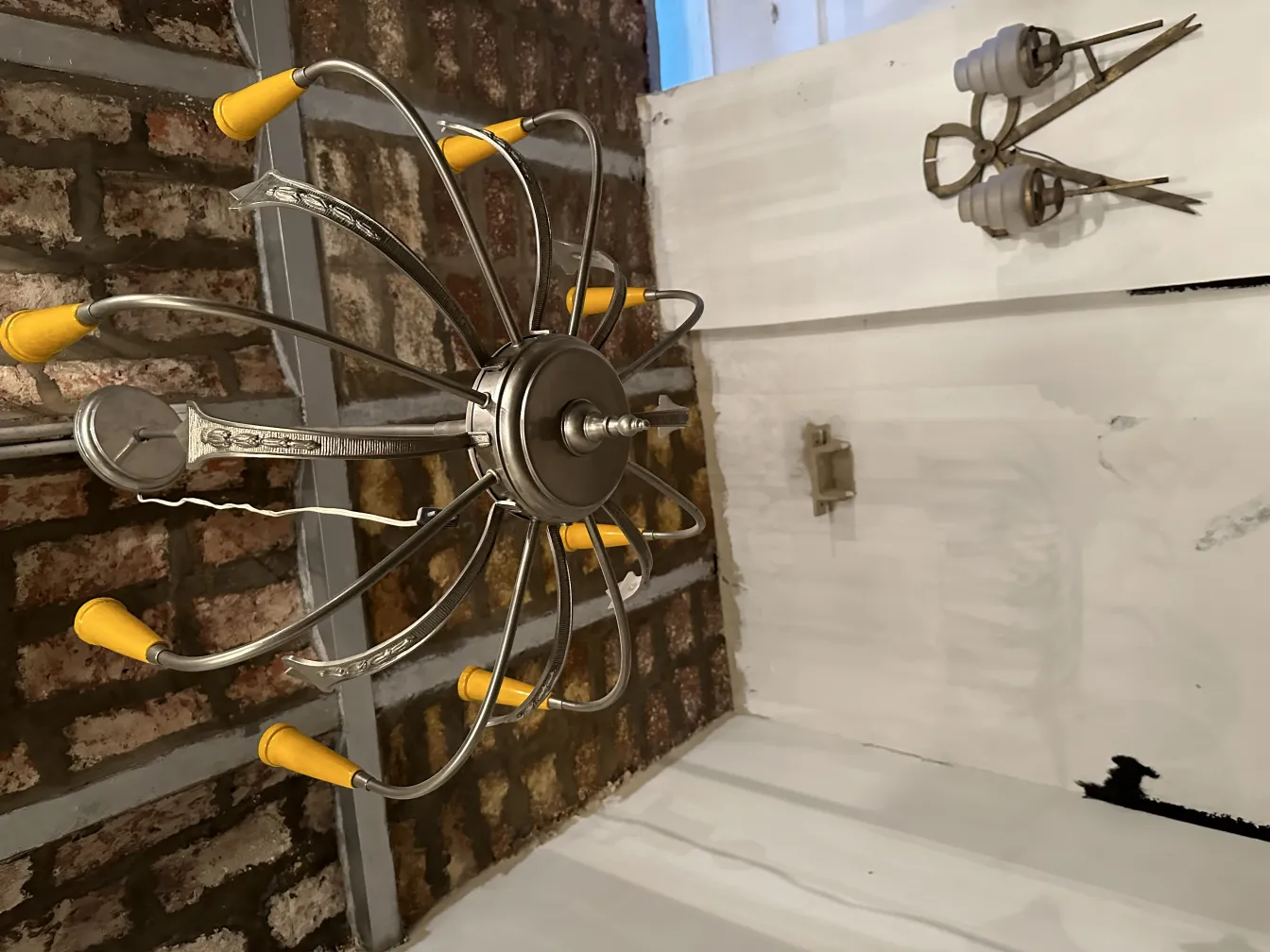 Antique hanging lamp with metal arms and bright details. Brick background.