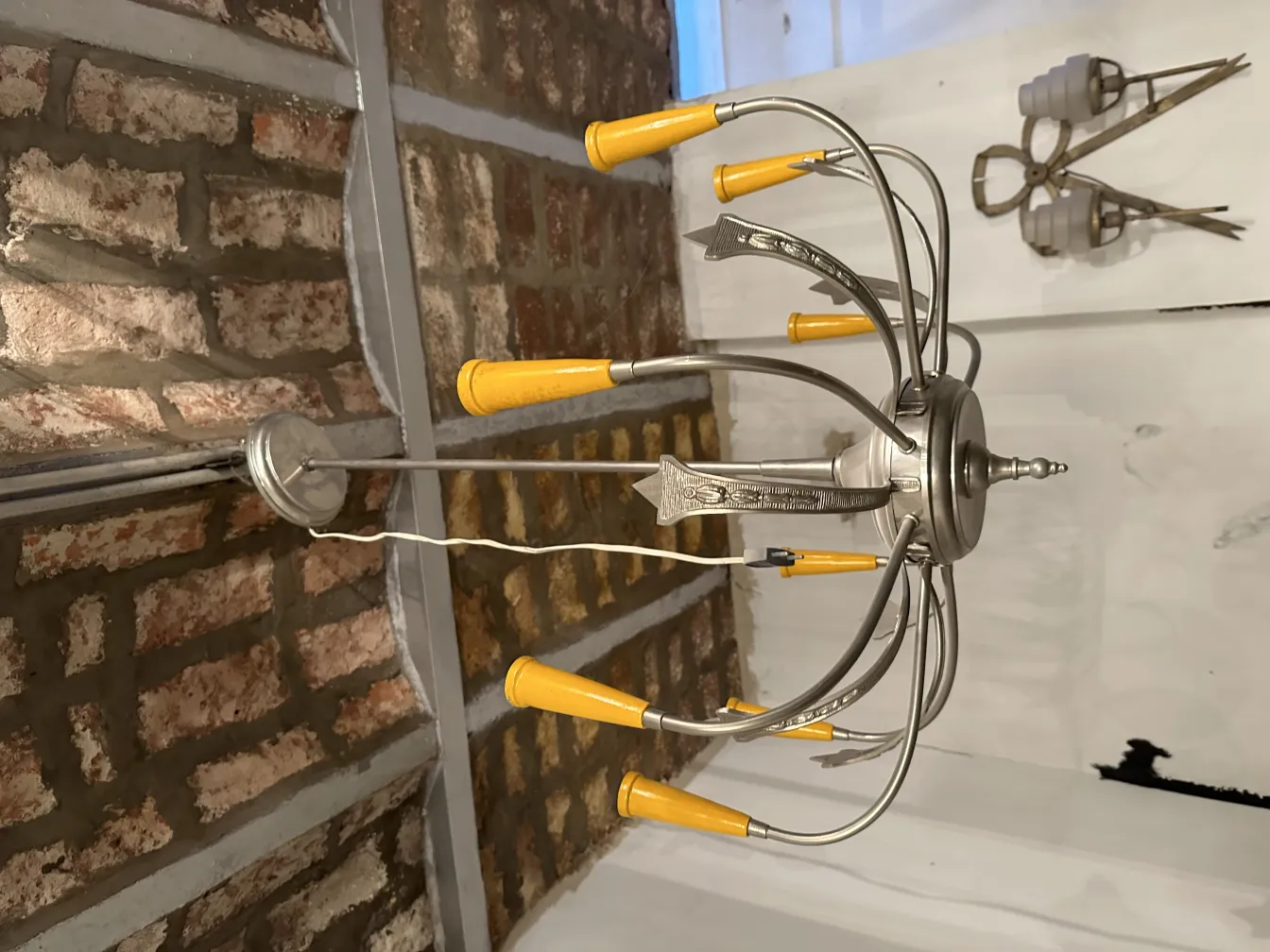 Lustre ancien avec abat-jours jaunes dans un cadre rustique.