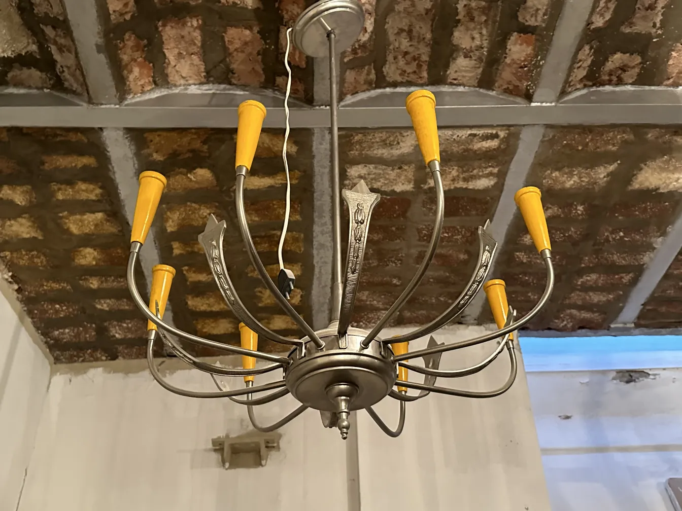 Antigua lámpara de techo con detalles decorativos y cápsulas naranjas, colgando en un techo de ladrillo expuesto.