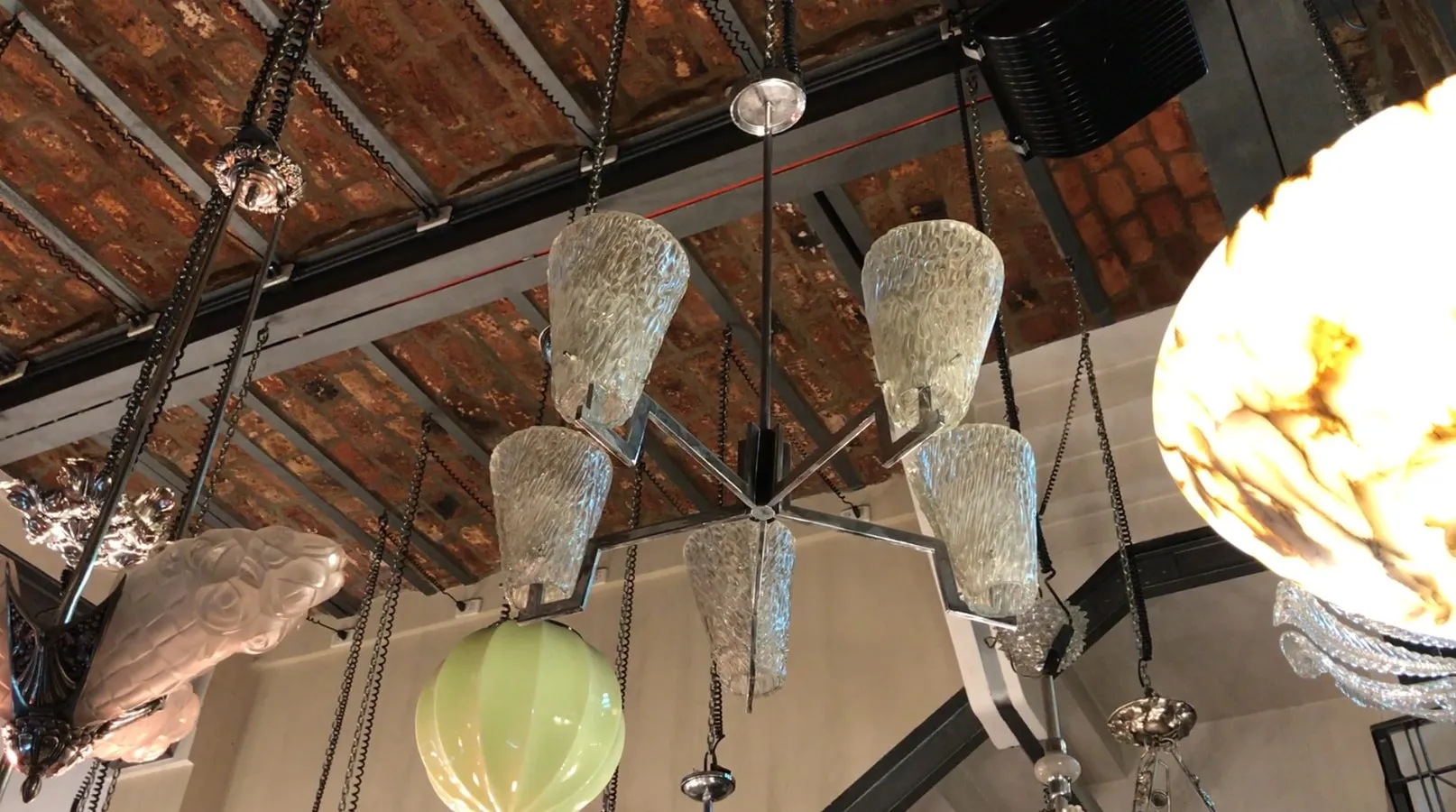 Lampada a sospensione antica con paralumi in vetro in un ambiente moderno.